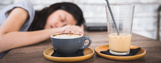 Woman feel asleep on a table with her two different cups of coffee