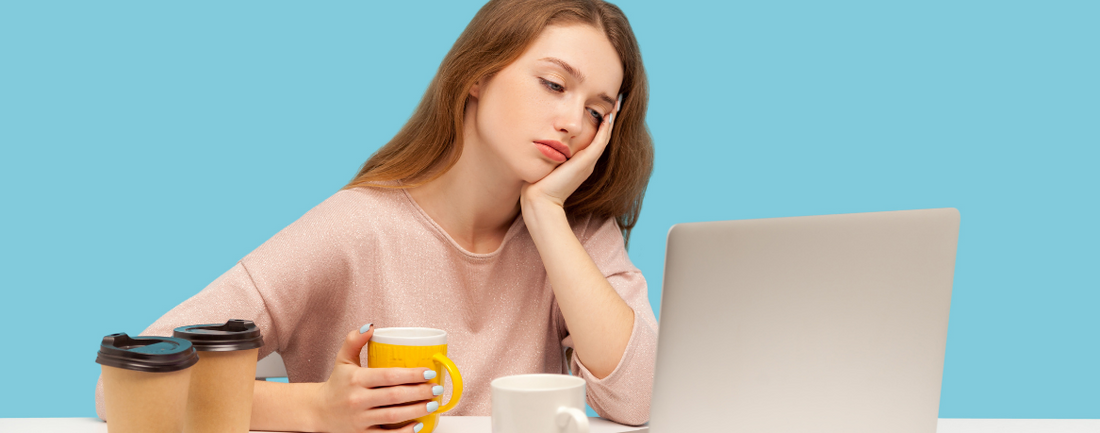 Tired woman in front of laptop holding coffee
